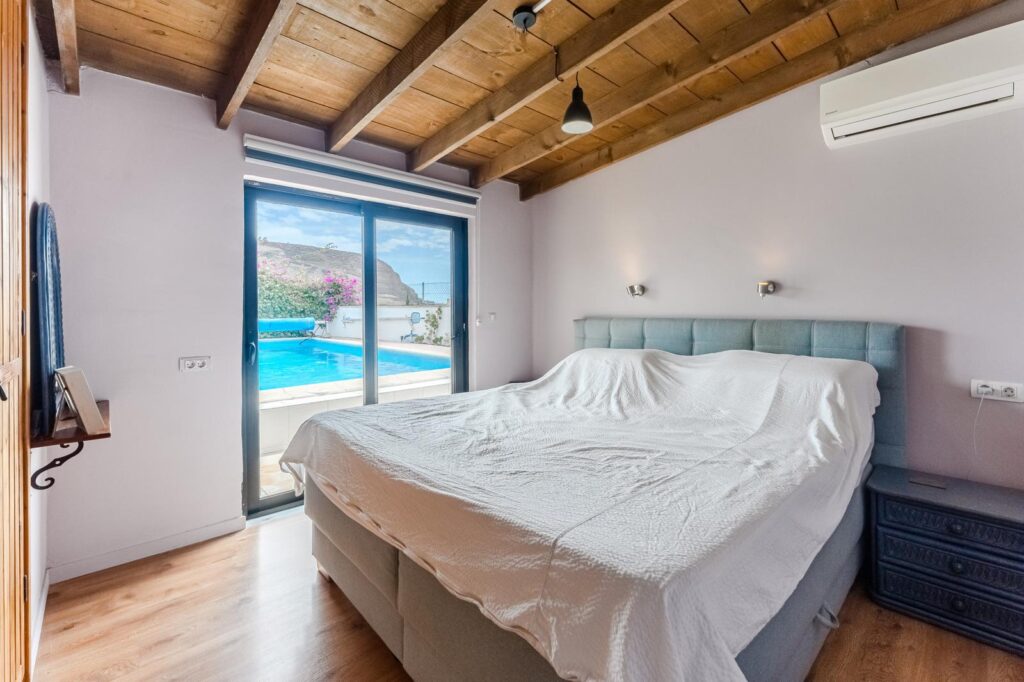 Dormitorio de matrimonio con salida a la piscina, techos de madera
