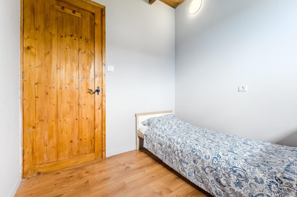 Dormitorio individual , puerta de madera natural